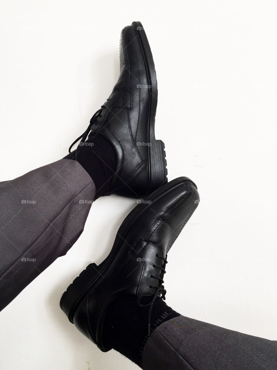 Close-up of man's feet wearing black shoes on white background