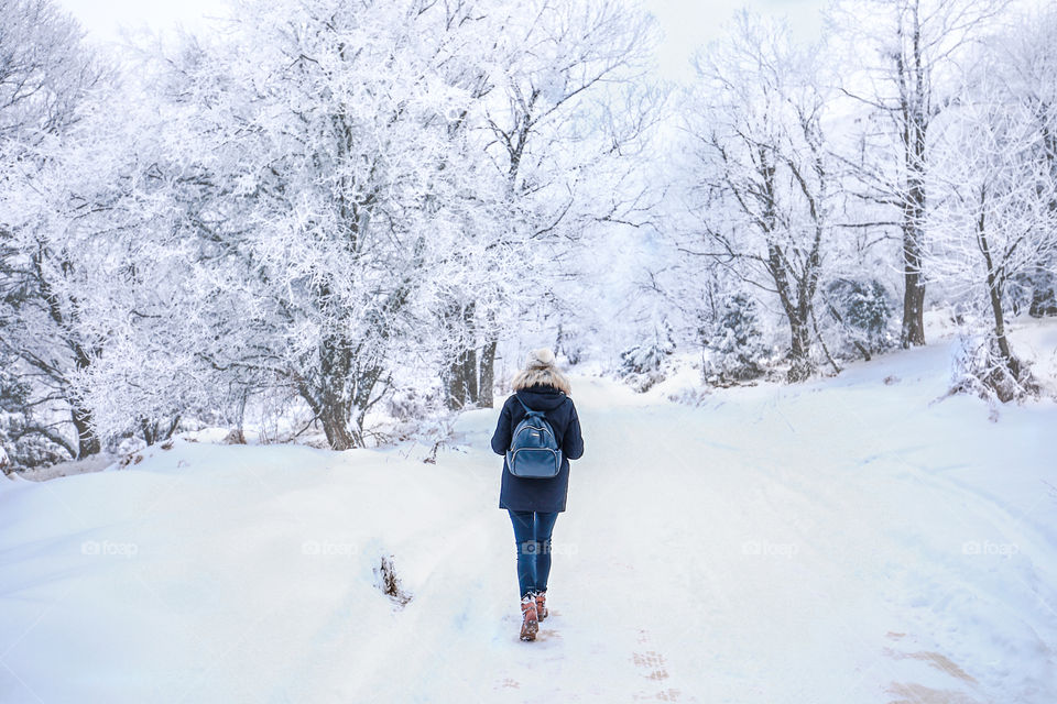 Young woman with a backpack walking in a snowy landscape.