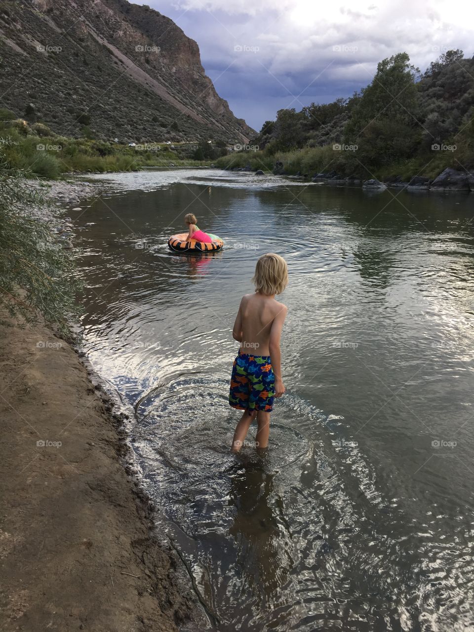 Children venturing out into the river to enjoy floating in a tube along the lazy current.