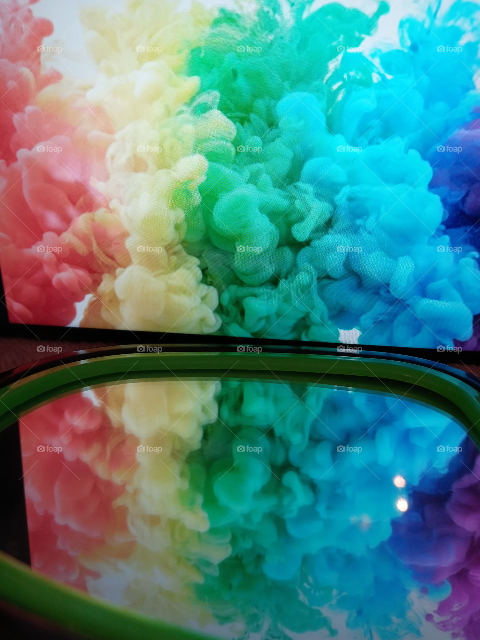 Humo con colores de arcoiris reflejado en un espejo.