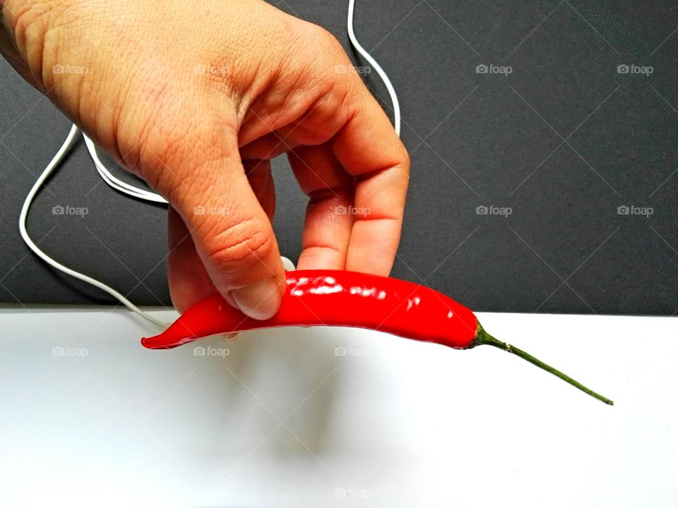 human hand is holding red chilli on black and white background