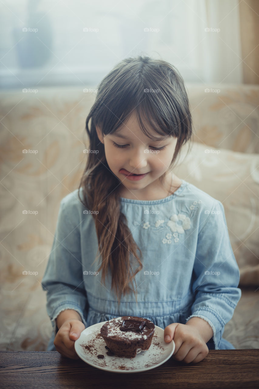 Little girl eating the chocolate muffin