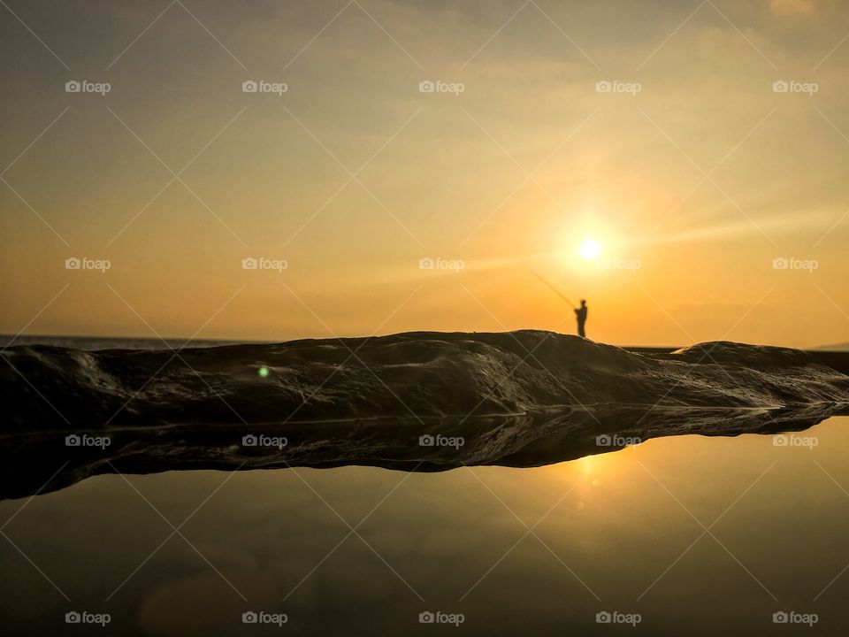 Silhouette of fisherman fishing during sunset. 