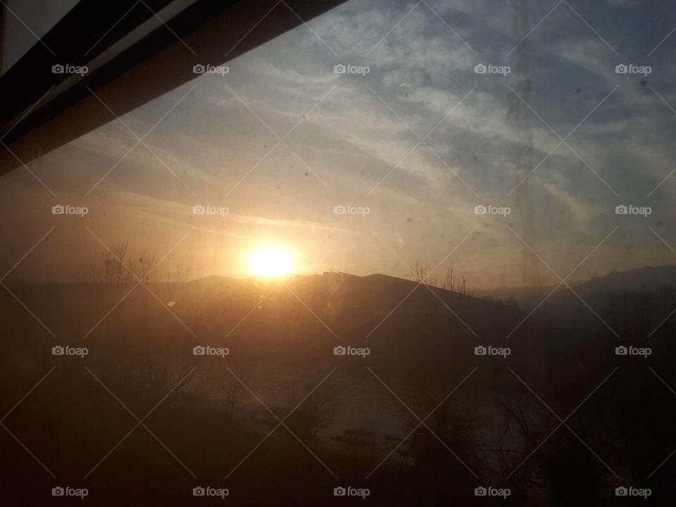 a view of the sunset through the window of the old passenger wagon