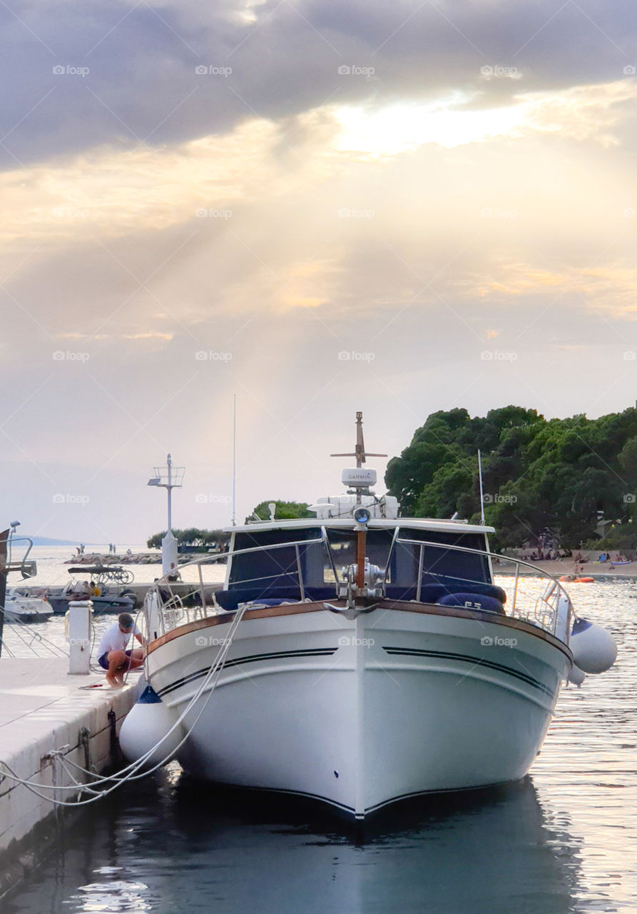 Croatia, Dalmatia, Brela.  Summer warm evening in the resort Adriatic town.  Marina, a young man washes a beautiful yacht.  Sea vacation