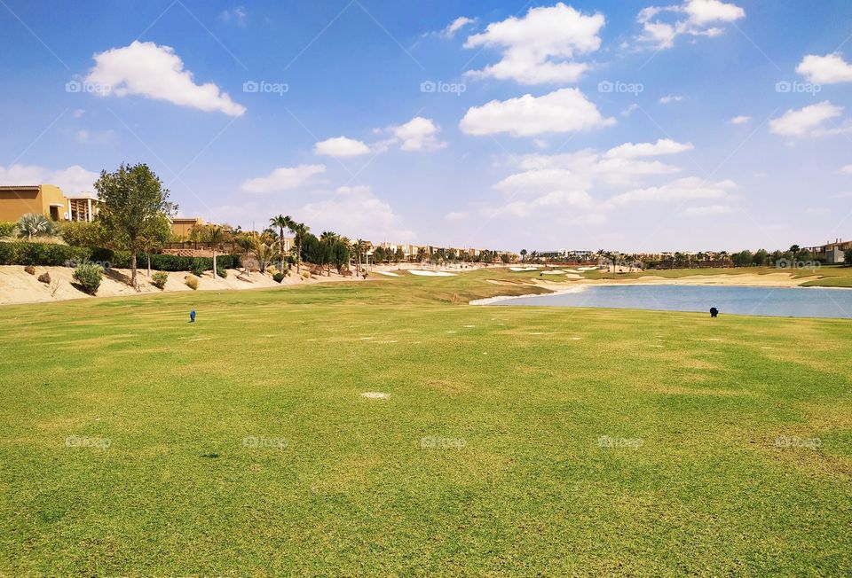 A beautiful view from the tee box on a golf hole with a lake, bunkers and trees on sand