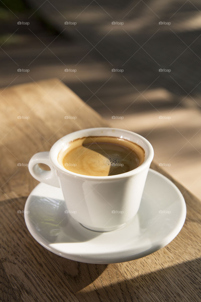 A cup of coffee on a wooden table.