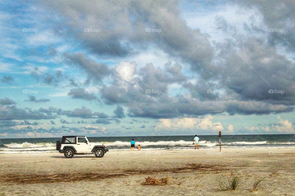 Beach drive. A white jeep driving on the beach 